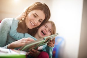 Mother and daughter reading a book and laughing