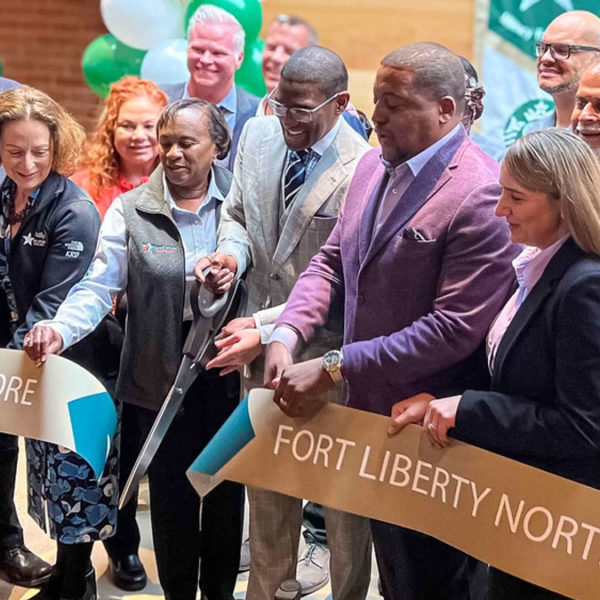 Kathy Roth-Douquet and others cutting banner at Fort Liberty Starbucks