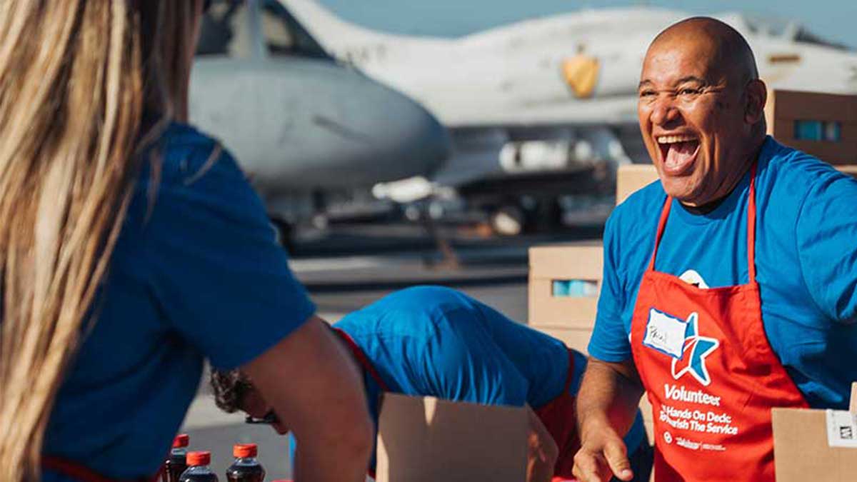 man-volunterring-placing-donations-in-box-in-front-of-military-aircraft