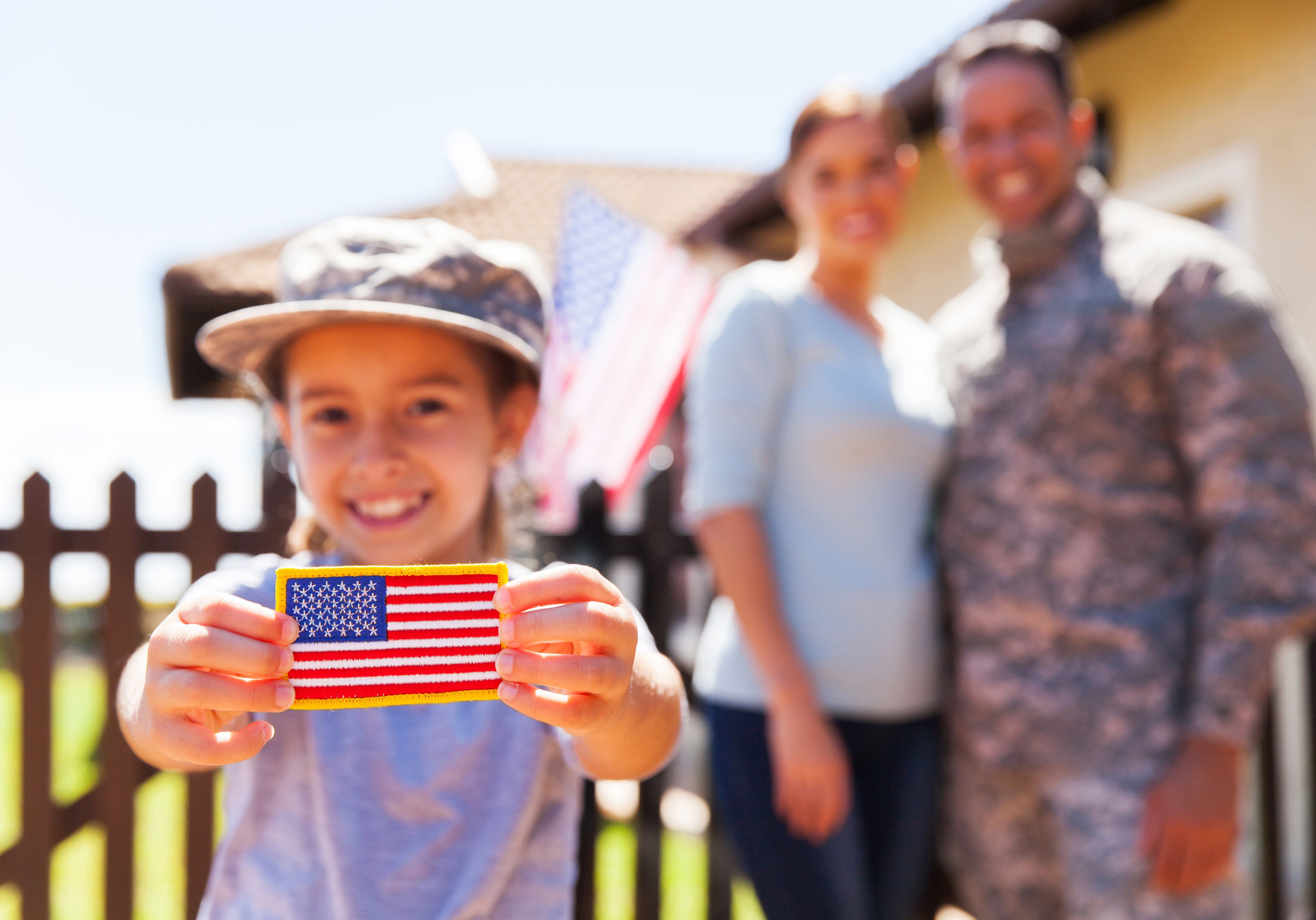 little girl holding american flag badge in front of parents