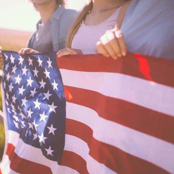 Cropped shot of a row of three youth holding an American flag with a vintage style develop outdoors