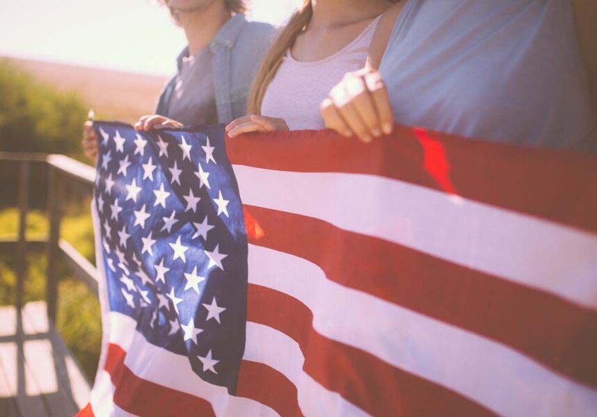 Cropped shot of a row of three youth holding an American flag with a vintage style develop outdoors
